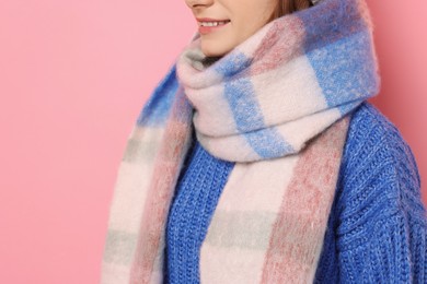 Photo of Woman in warm scarf on pink background, closeup. Space for text