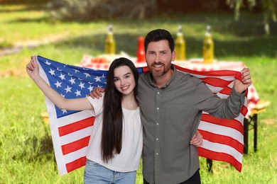 Image of 4th of July - Independence day of America. Happy father and daughter with national flag of United States having picnic in park