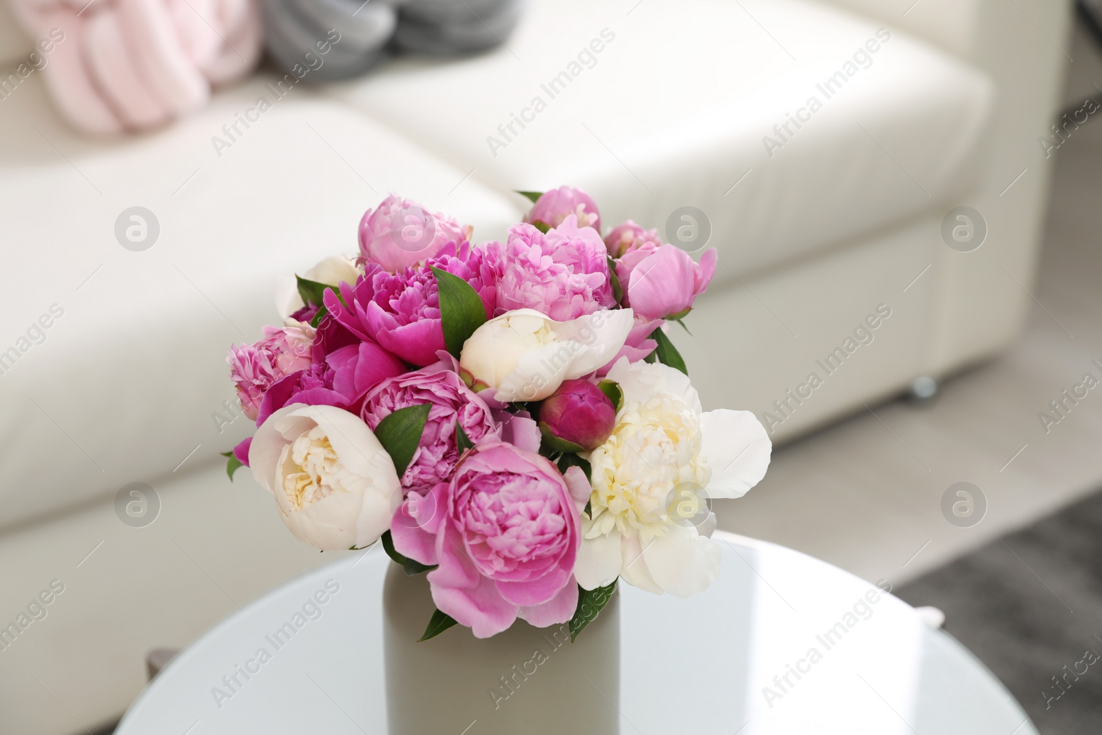 Photo of Vase with bouquet of beautiful peonies on table in room