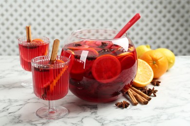 Photo of Bowl of delicious aromatic punch drink, ingredients and glasses on white marble table