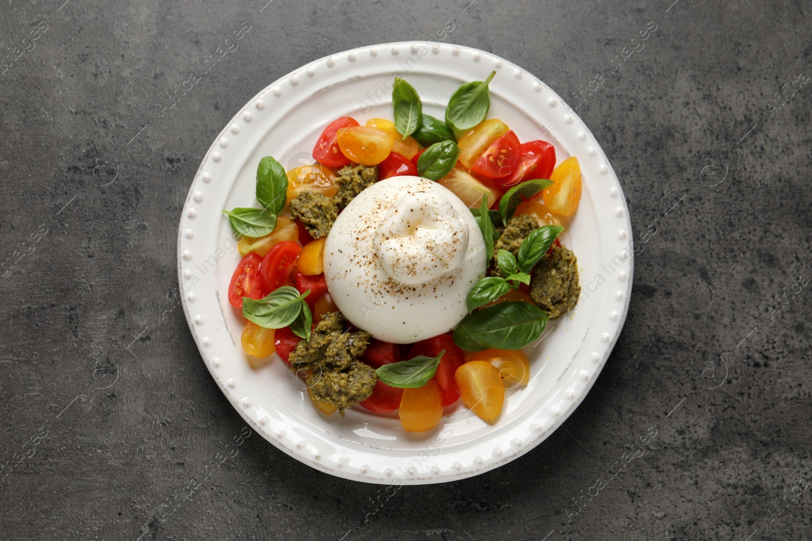 Photo of Delicious burrata salad on grey table, top view