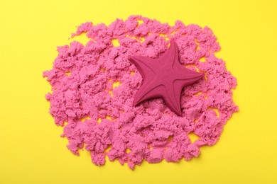 Star made of kinetic sand on yellow background, flat lay