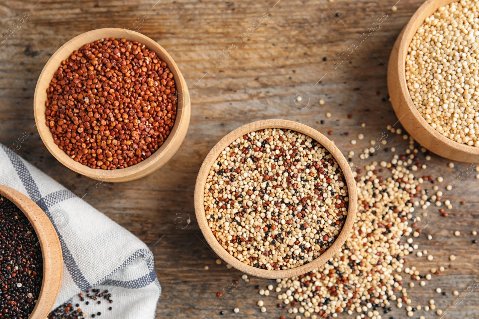 Photo of Bowls with different types of quinoa on wooden background, top view