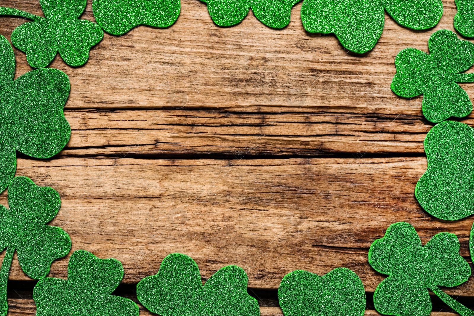 Photo of Frame of clover leaves on wooden background, flat lay with space for text. St. Patrick's Day celebration