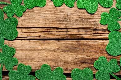 Frame of clover leaves on wooden background, flat lay with space for text. St. Patrick's Day celebration