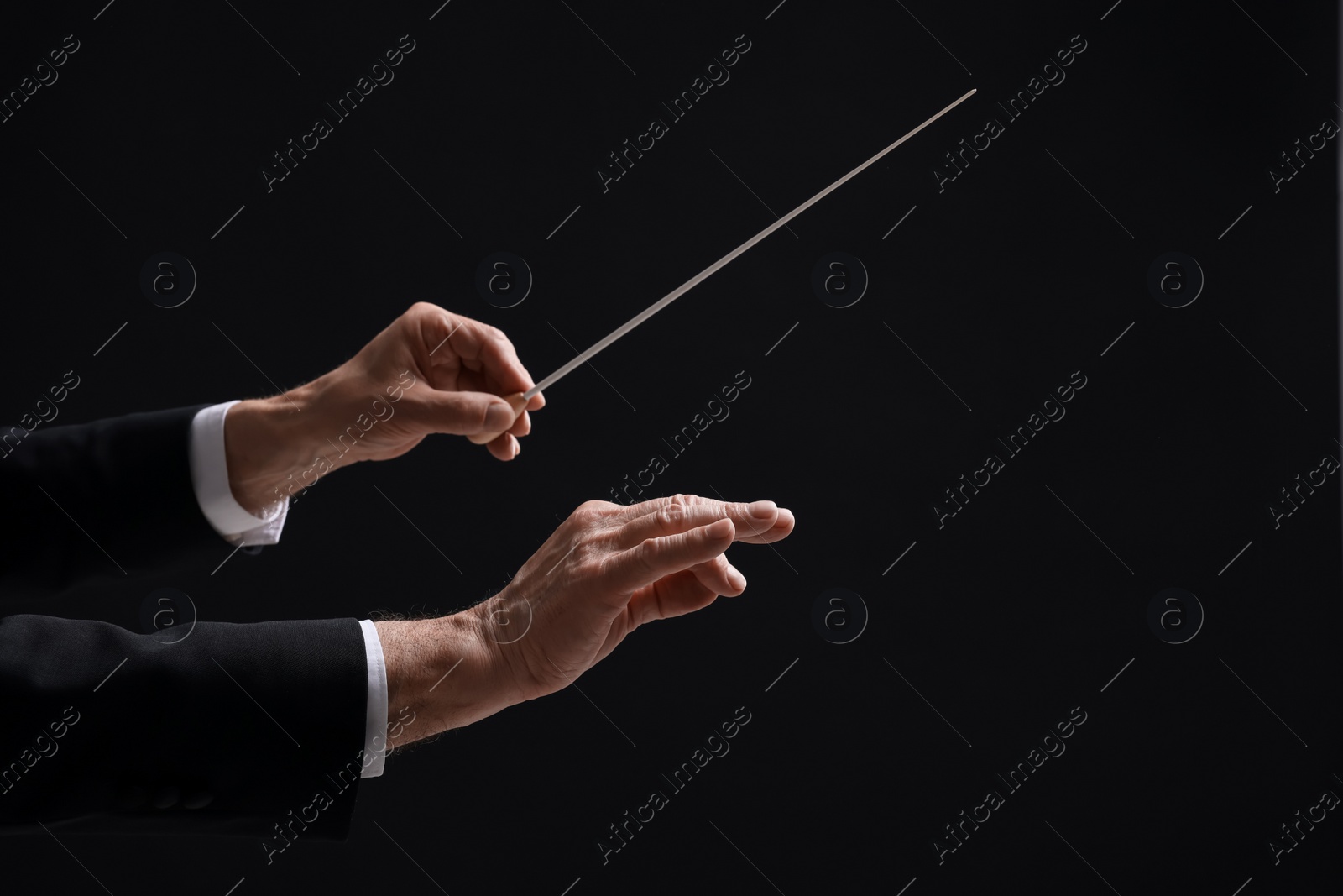 Photo of Professional conductor with baton on black background, closeup