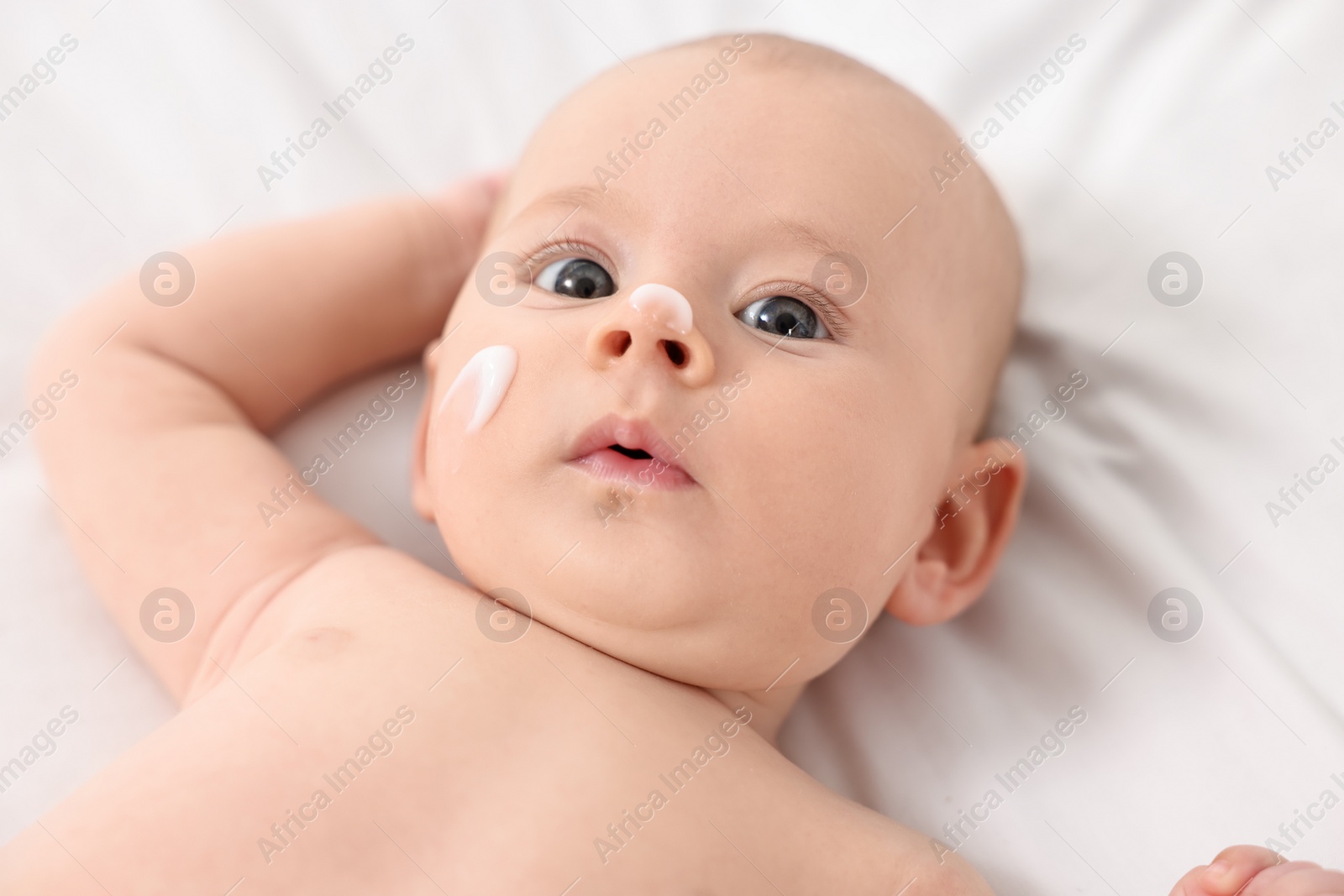 Photo of Cute little baby with cream on face on white blanket