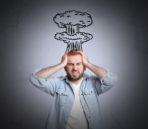 Image of Young man having headache on light grey background. Illustration of atomic explosion representing severe pain