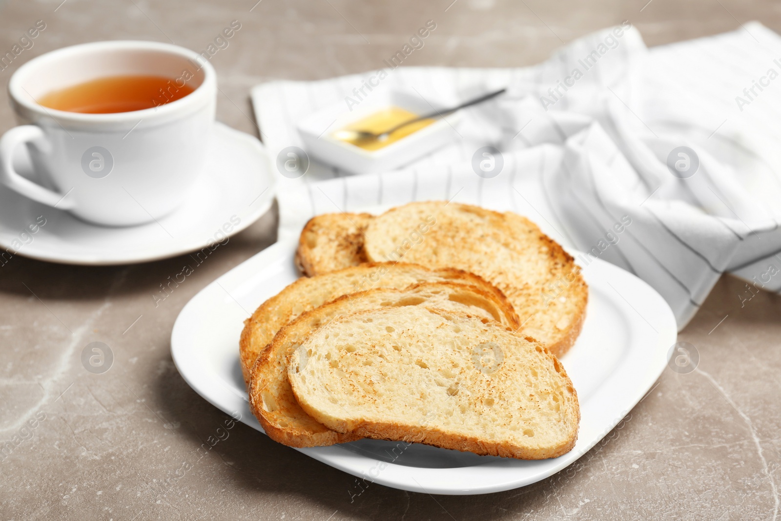 Photo of Plate with toasted bread and cup of tea on grey background