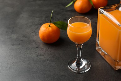 Photo of Delicious tangerine liqueur and fresh fruits on grey table, space for text