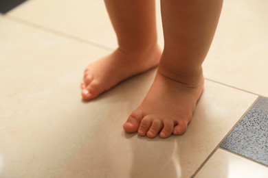 Cute baby learning to walk indoors, closeup