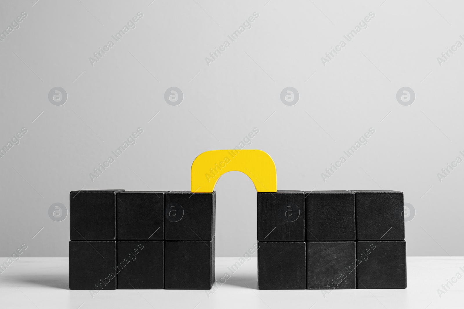 Photo of Bridge made of colorful blocks on white table. Connection, relationships and deal concept