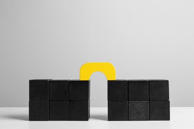 Photo of Bridge made of colorful blocks on white table. Connection, relationships and deal concept