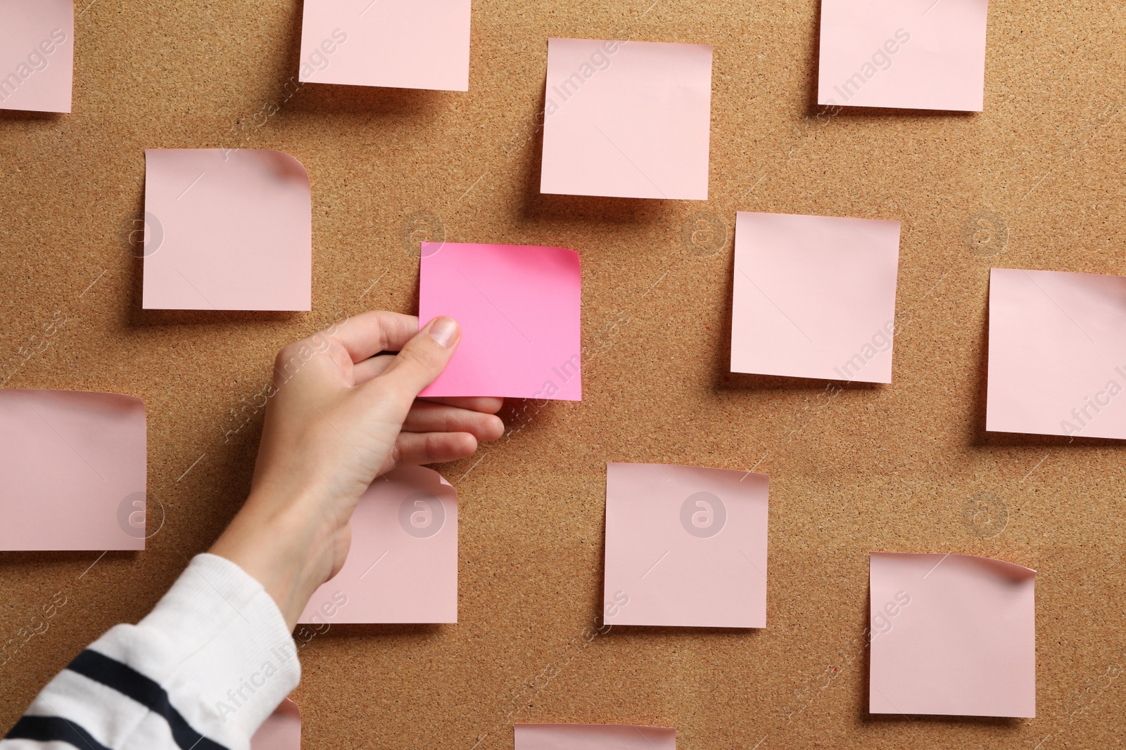 Photo of Woman taking empty paper note from cork board, closeup