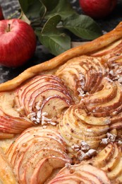 Photo of Tasty apple pie, fresh fruits and green leaves on table, closeup