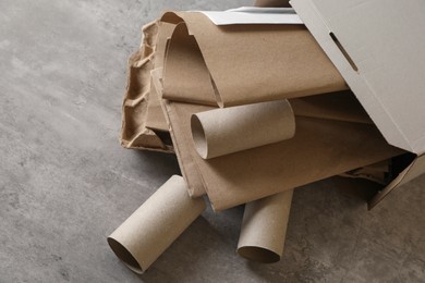 Photo of Box with different waste paper on grey table, closeup