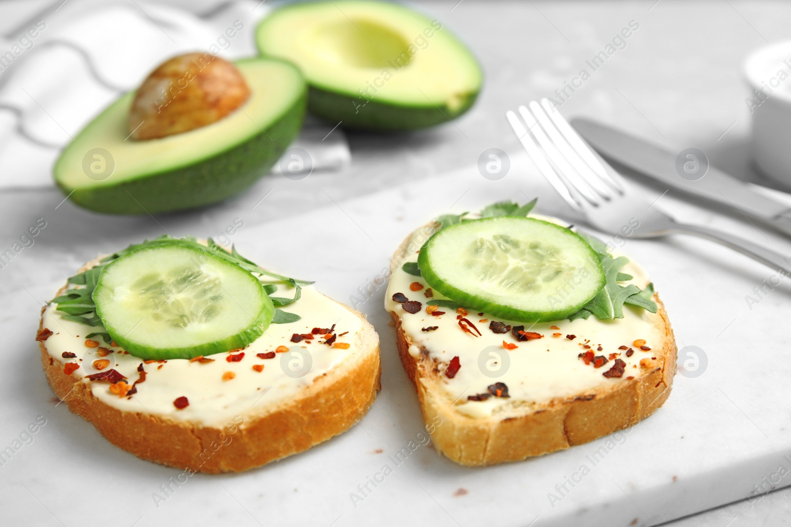 Photo of Slices of bread with spread and cucumber on board