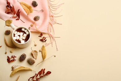 Photo of Flat lay composition with cup of hot drink, scarf and autumn leaves on beige background, space for text. Cozy atmosphere