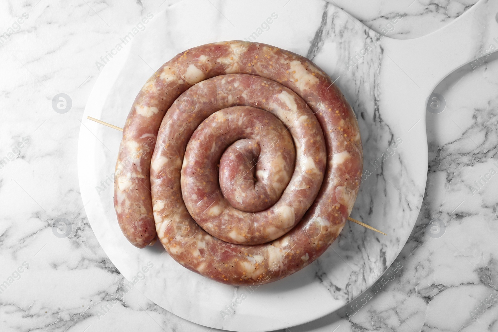 Photo of Raw homemade sausage on white marble table, top view