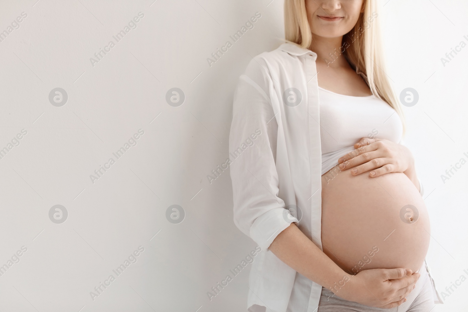 Photo of Pregnant woman on light background, closeup. Space for text