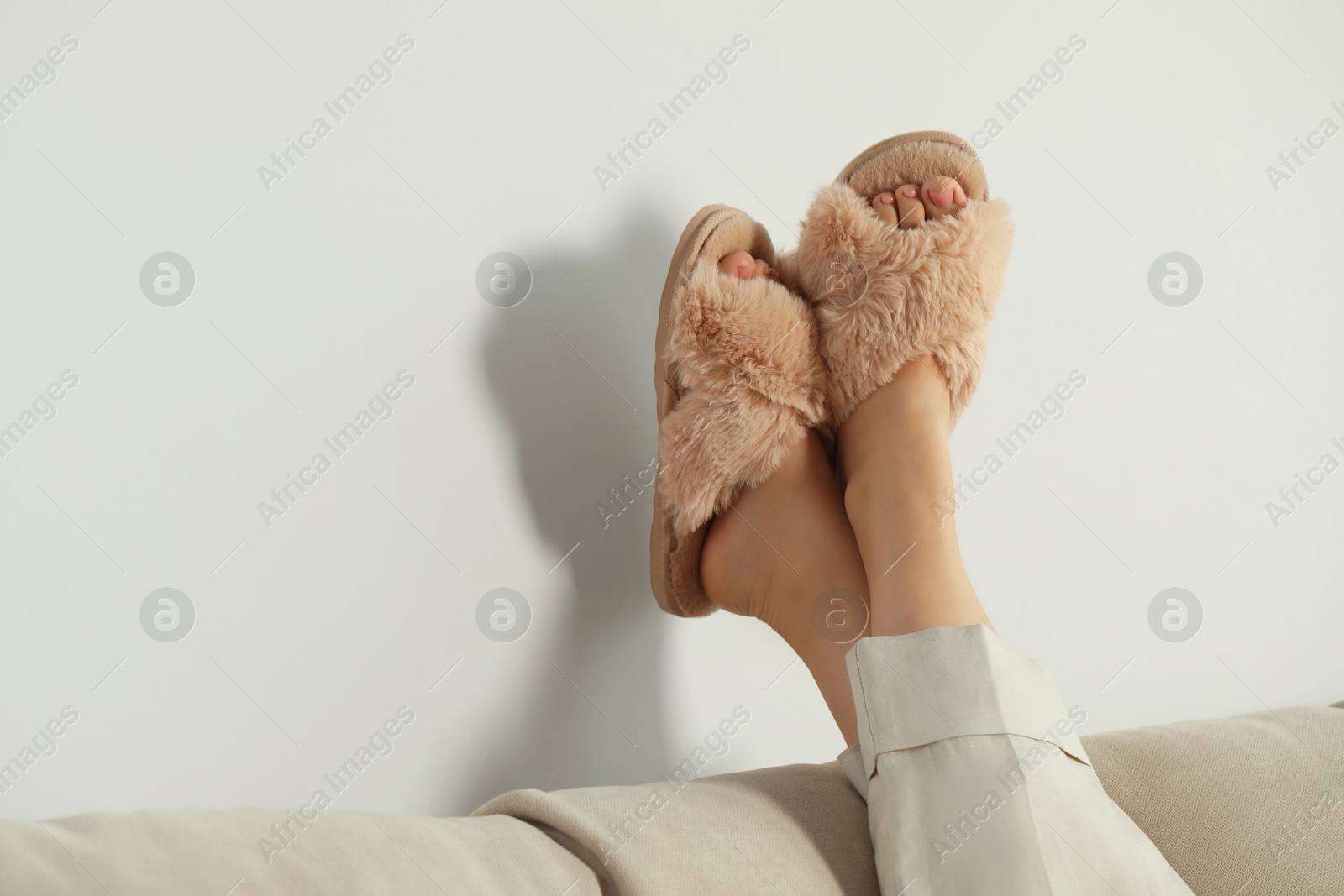 Photo of Woman wearing soft comfortable slippers at home, closeup. Space for text