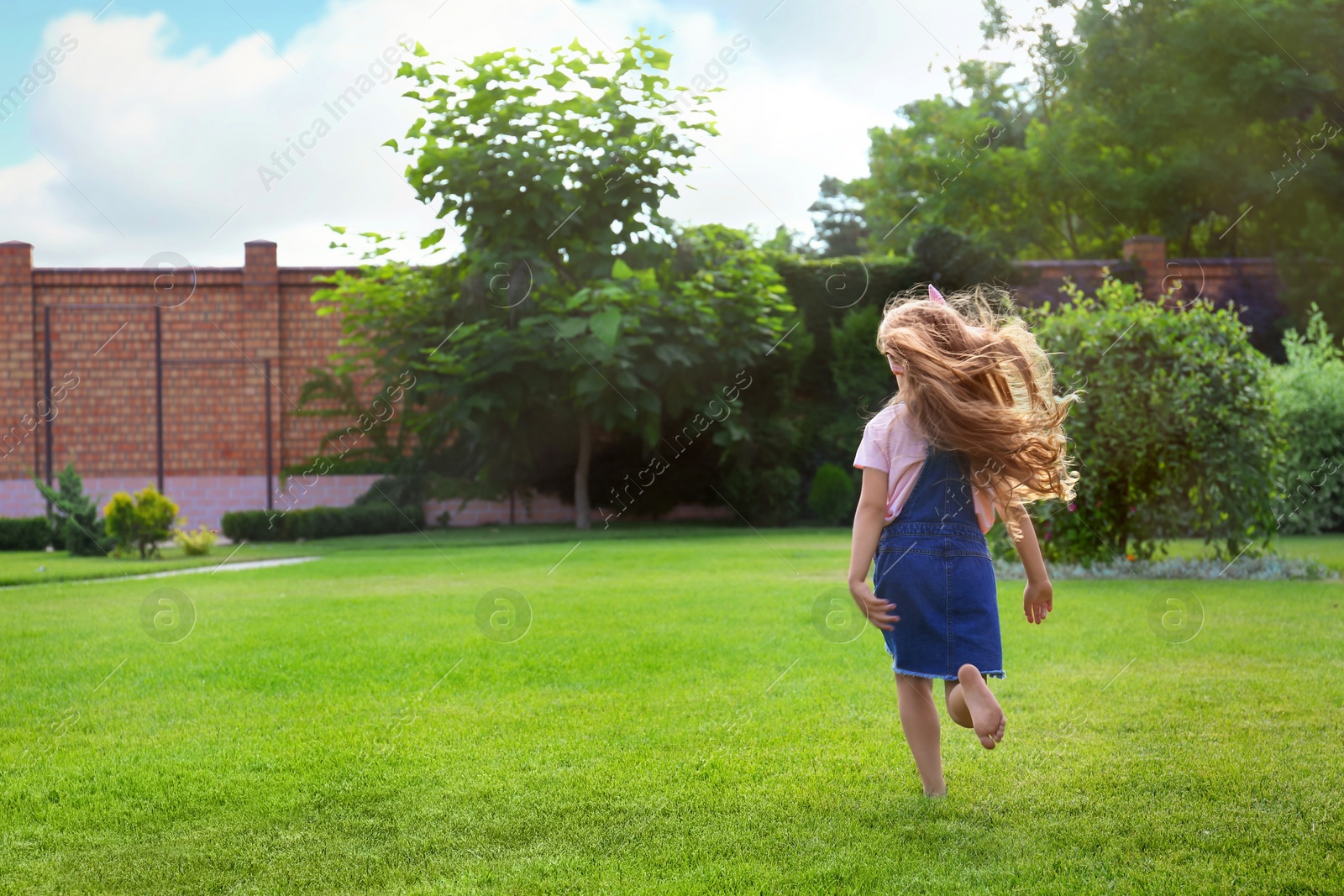 Photo of Cute little girl running in green park on summer day