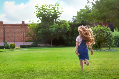 Cute little girl running in green park on summer day