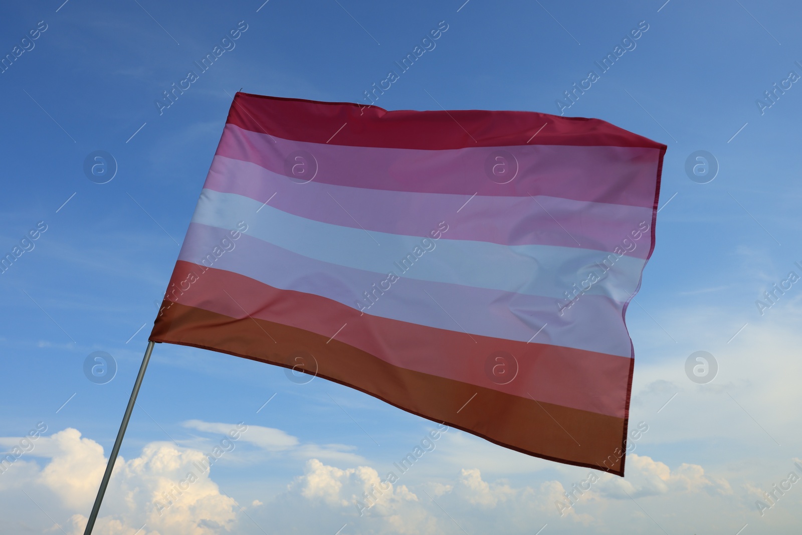 Photo of Bright lesbian flag fluttering against blue sky