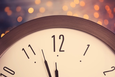 Photo of Clock on color background with blurred lights, closeup. New Year countdown