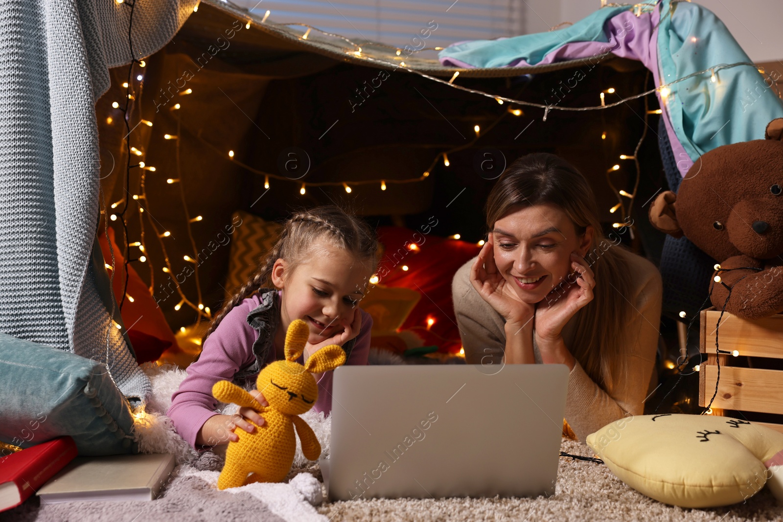 Photo of Mother and her daughter with laptop in play tent at home