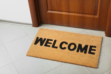 Photo of Door mat with word Welcome on floor near entrance, above view