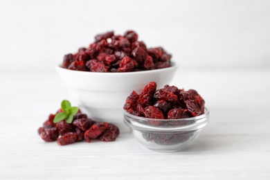 Tasty dried cranberries in bowls on white table