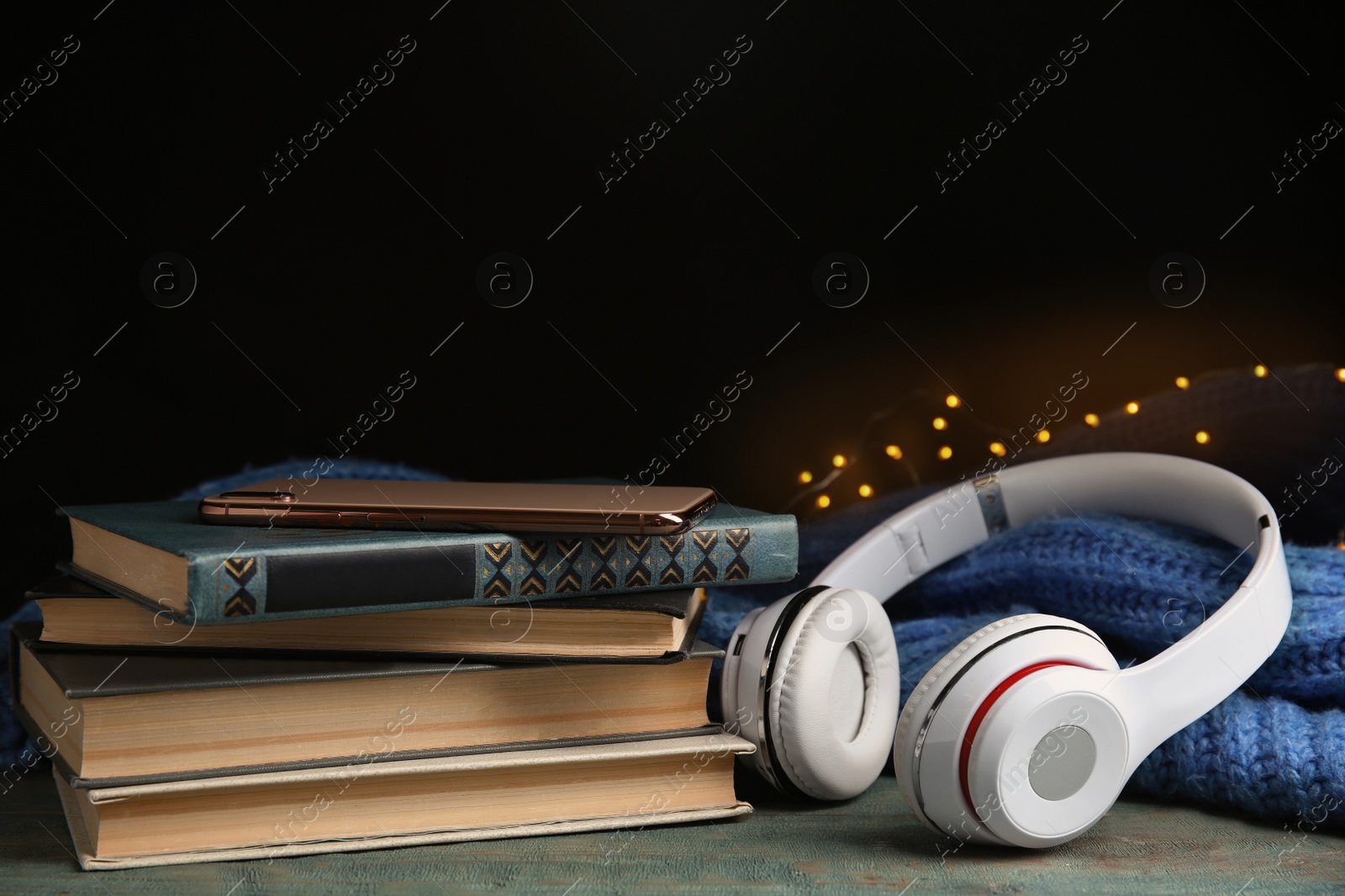 Photo of Books, headphones and mobile phone on light blue wooden table