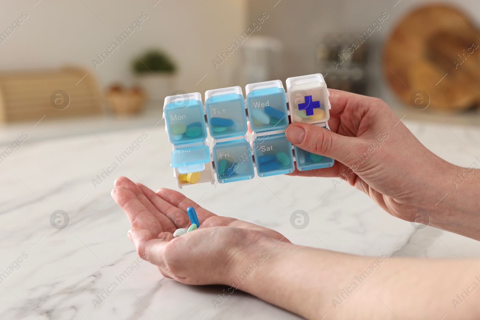 Photo of Woman with pills and organizer at white marble table, closeup