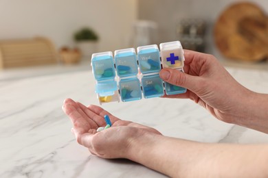 Photo of Woman with pills and organizer at white marble table, closeup