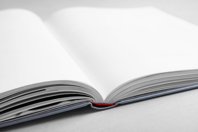 Open book with hard cover on light grey table, closeup