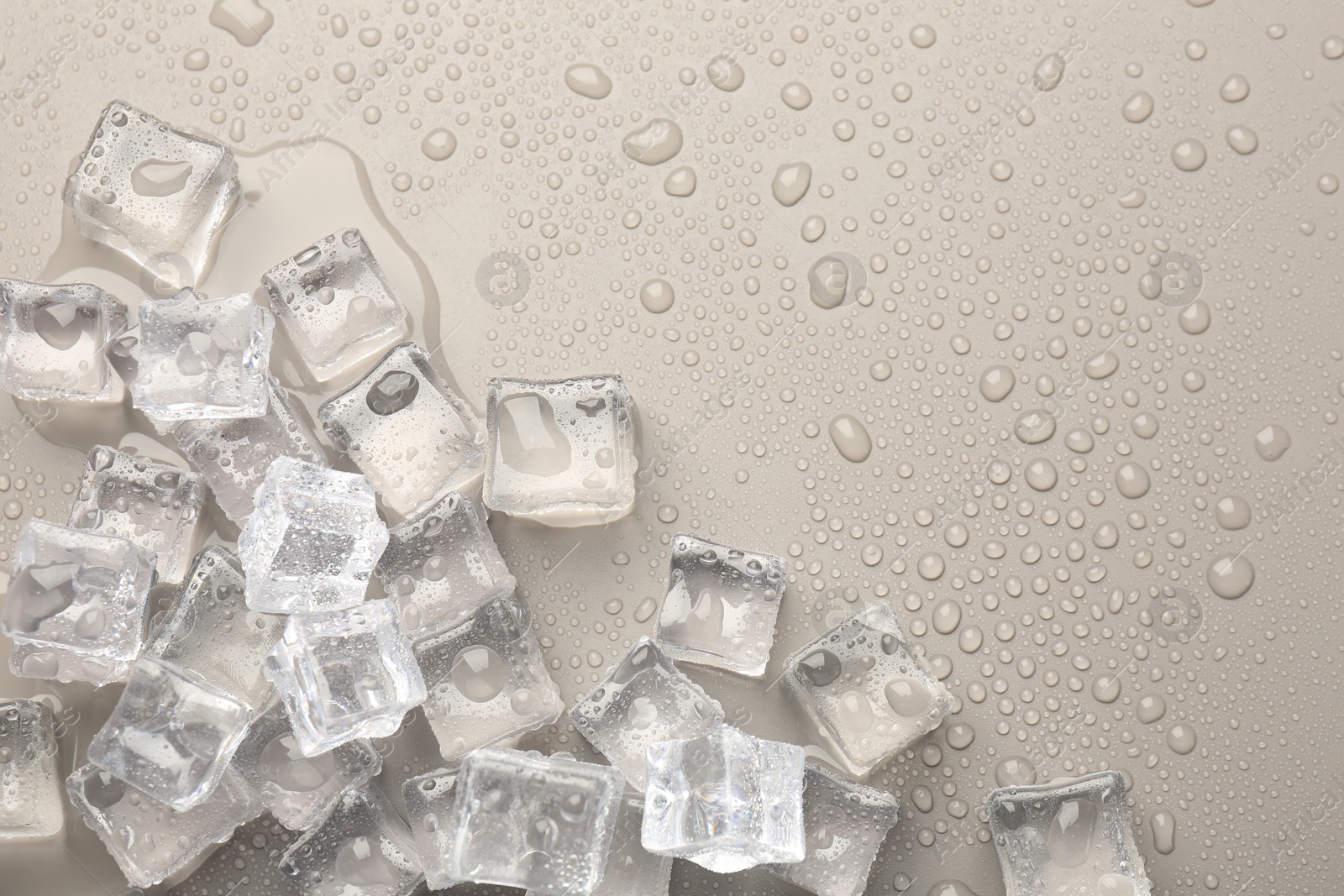 Photo of Melting ice cubes and water drops on light grey background, flat lay. Space for text