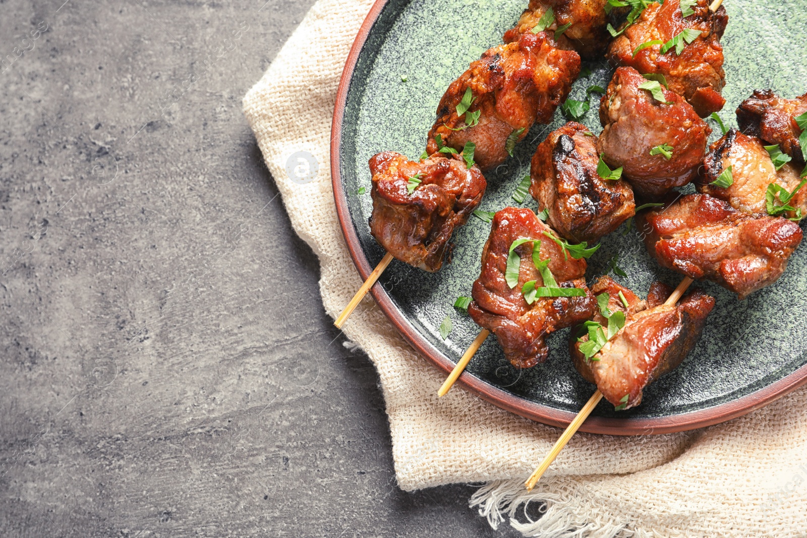 Photo of Plate of delicious barbecued meat on gray background, top view. Space for text