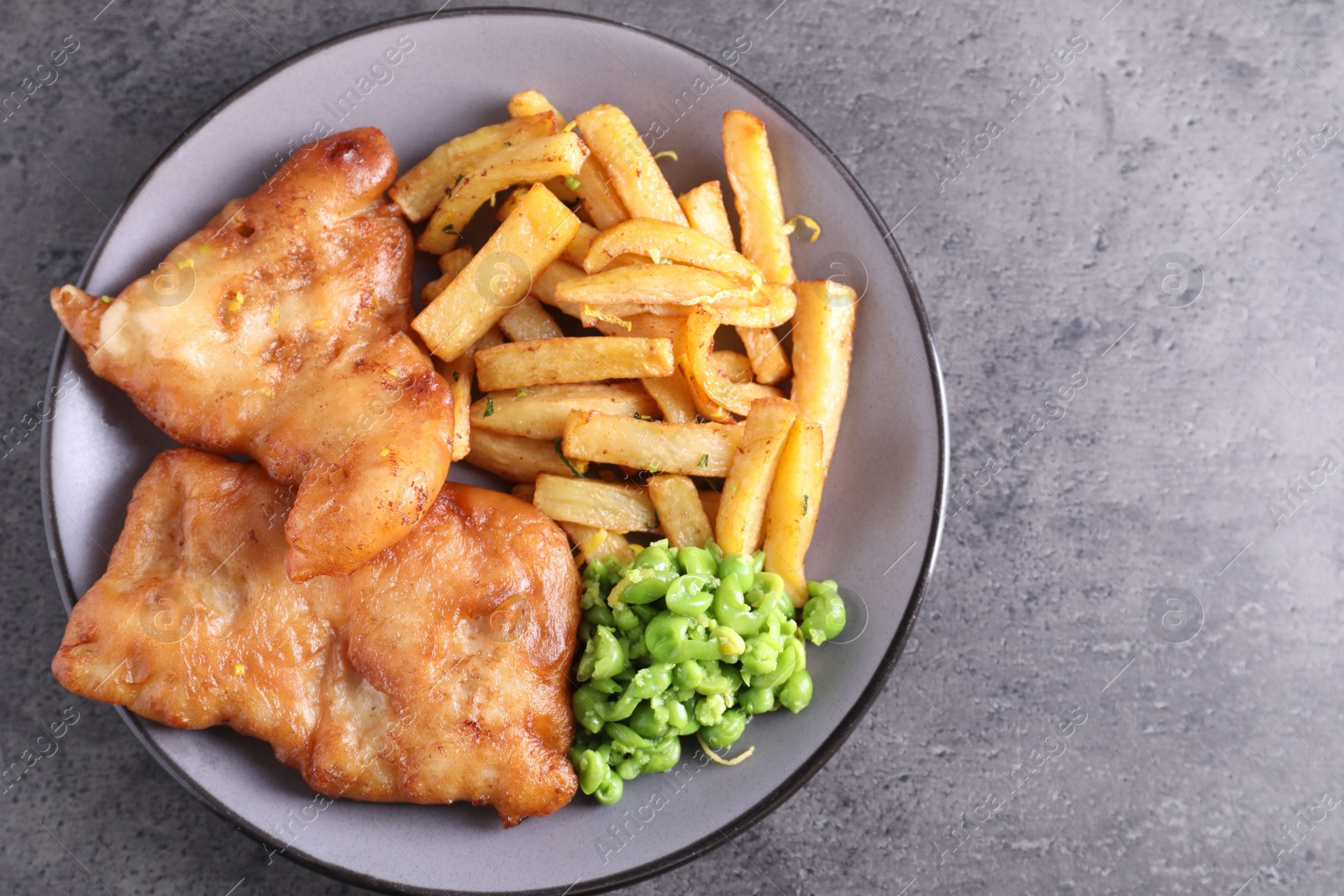 Photo of Tasty fish, chips and peas on grey table, top view. Space for text