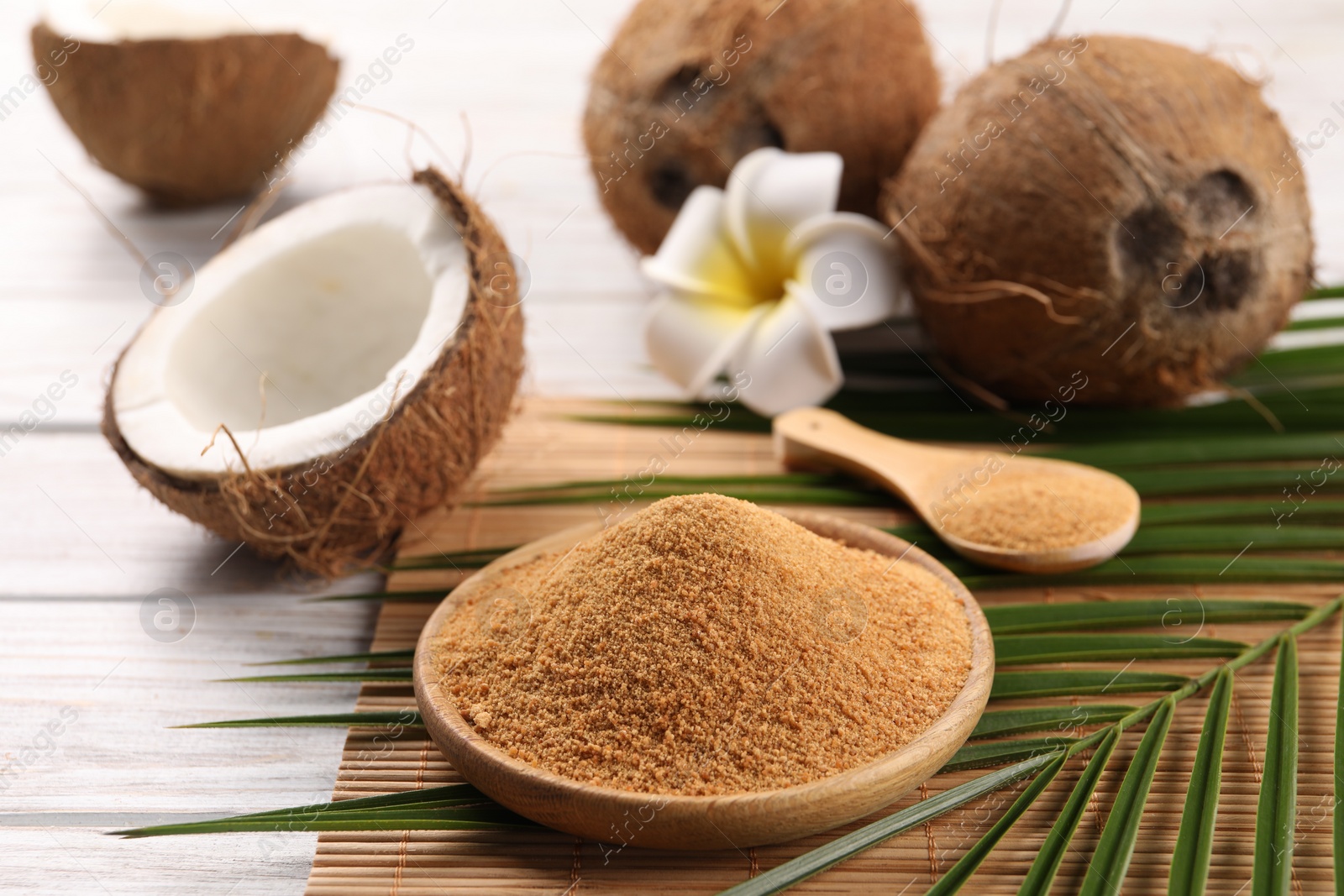 Photo of Coconut sugar, palm leaves, fruits and bamboo mat on wooden rustic table, closeup