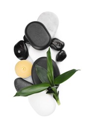 Spa stones, candle and bamboo leaves on white background, top view