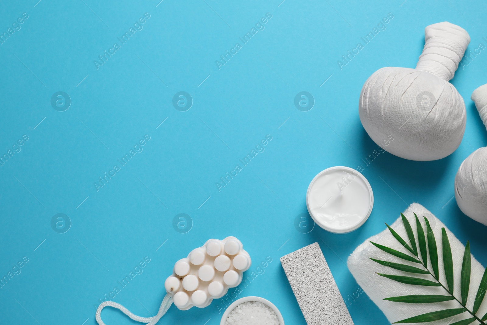 Photo of Beautiful spa composition with herbal massage bags and different care products on light blue background, flat lay. Space for text