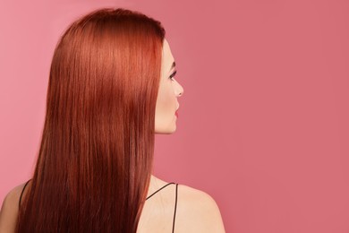 Photo of Beautiful woman with red dyed hair on pink background, back view. Space for text