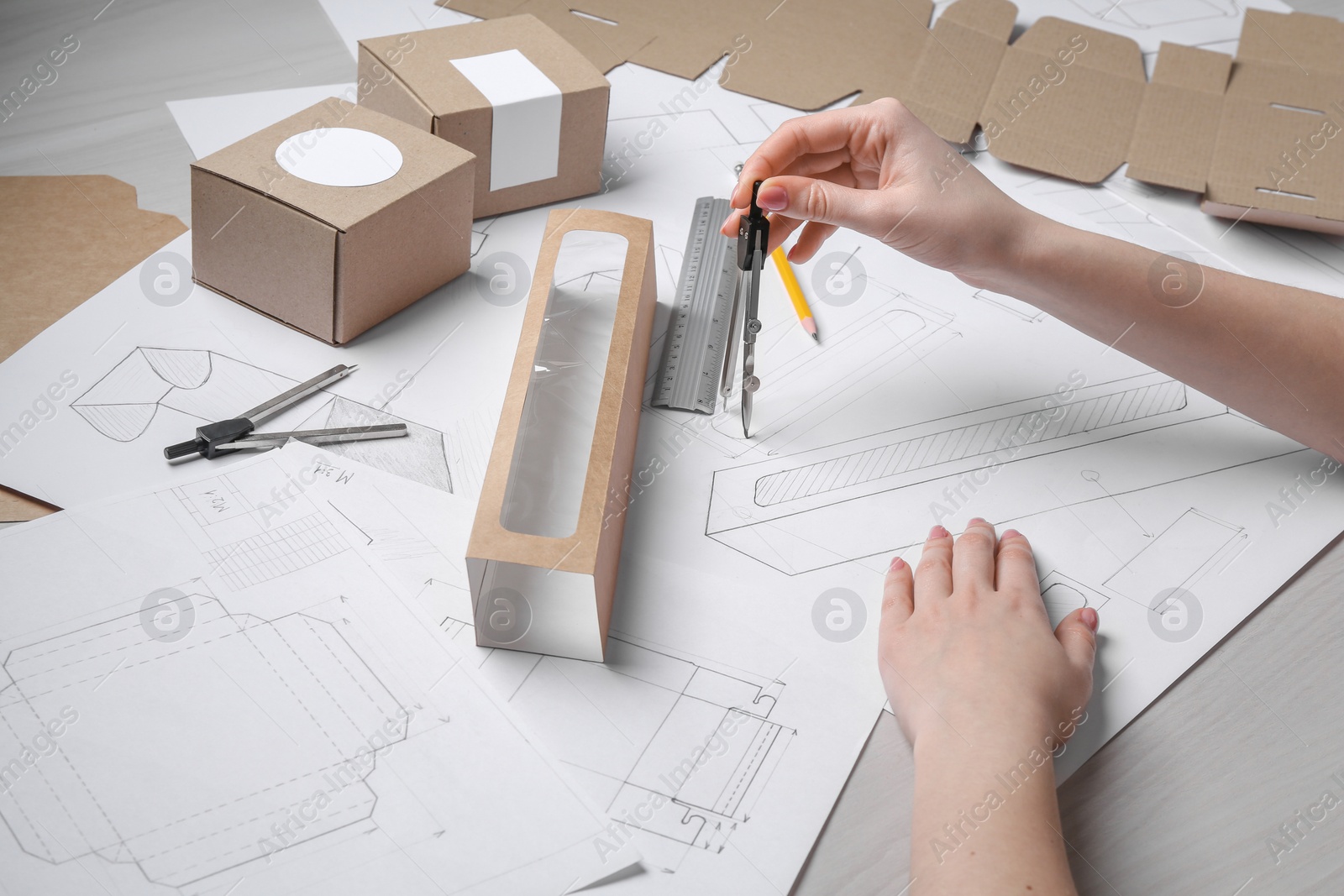 Photo of Woman creating packaging design at light wooden table, closeup