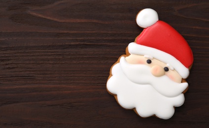 Photo of Santa Claus shaped Christmas cookie on wooden table, top view. Space for text