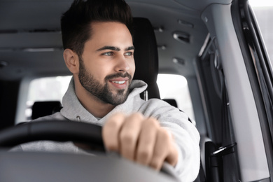 Handsome young man driving his modern car