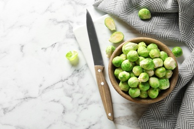 Photo of Bowl with fresh Brussels sprouts on marble table, top view. Space for text