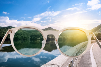 Road along lake on sunny day, view through sunglasses