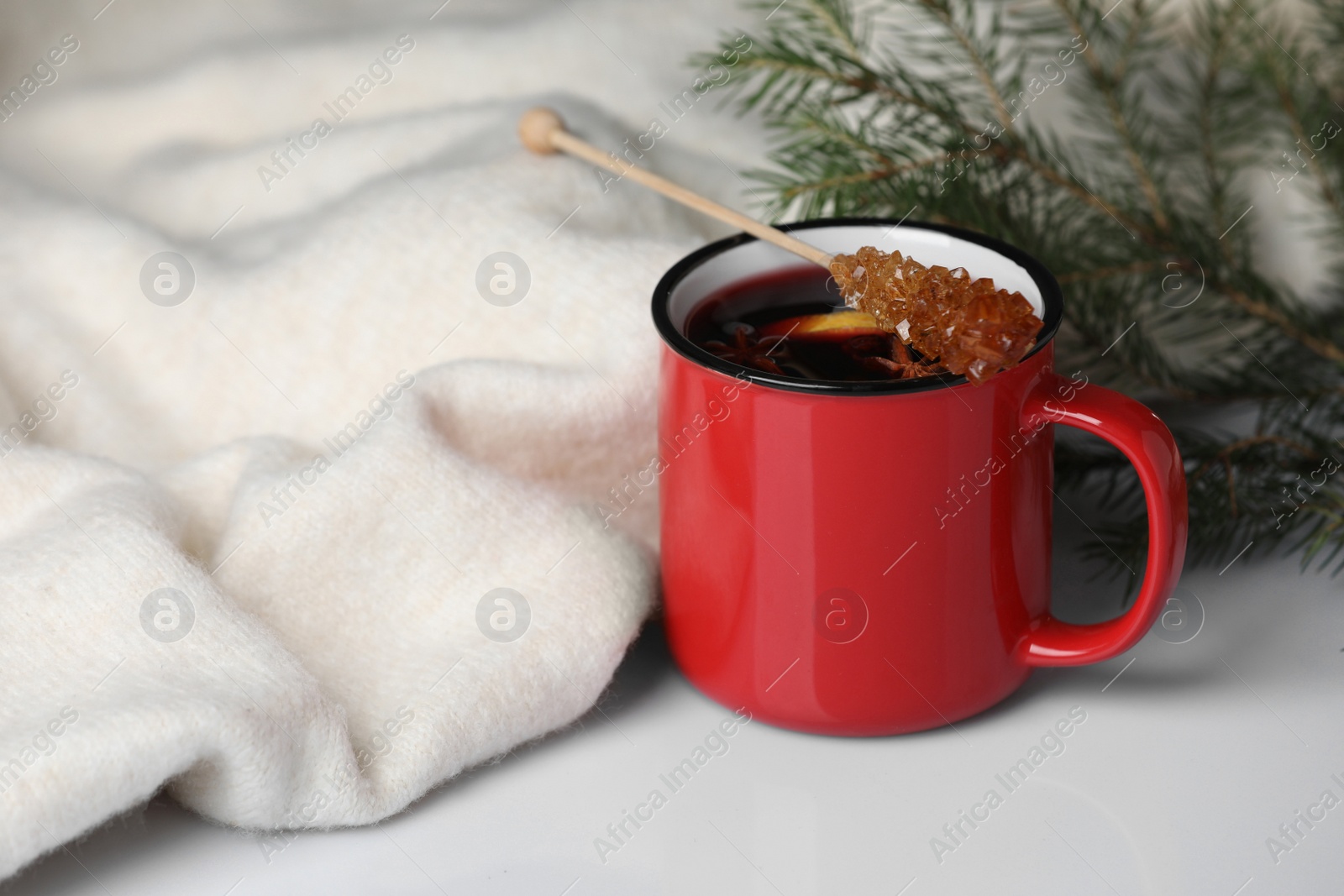 Photo of Stick with sugar crystals and cup of drink on white table