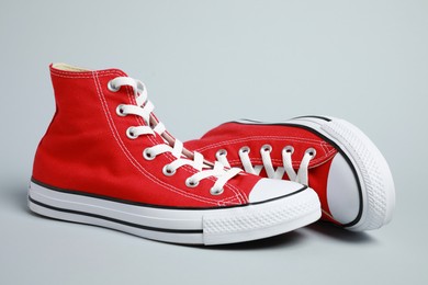 Photo of Pair of new stylish red sneakers on light grey background